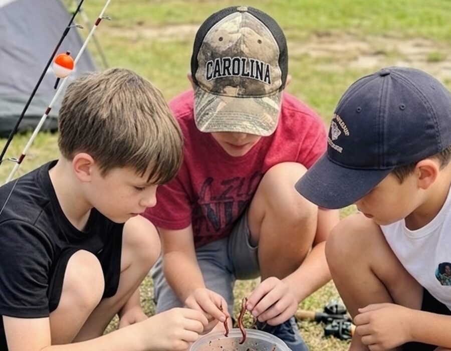 Three boys learning to bait a hook at an RHF beginner fishing clinic